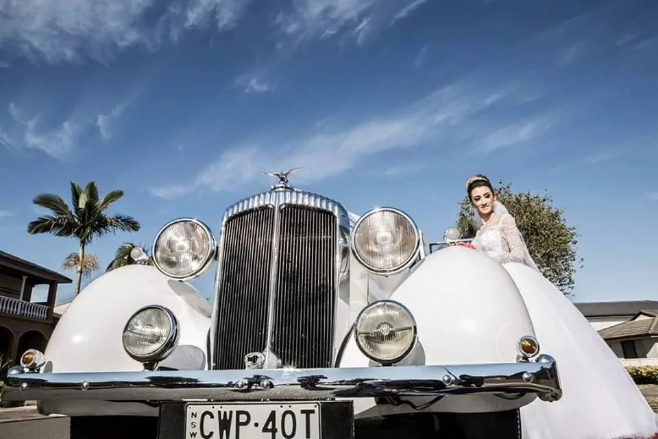 Bride beside white Bentley wedding car