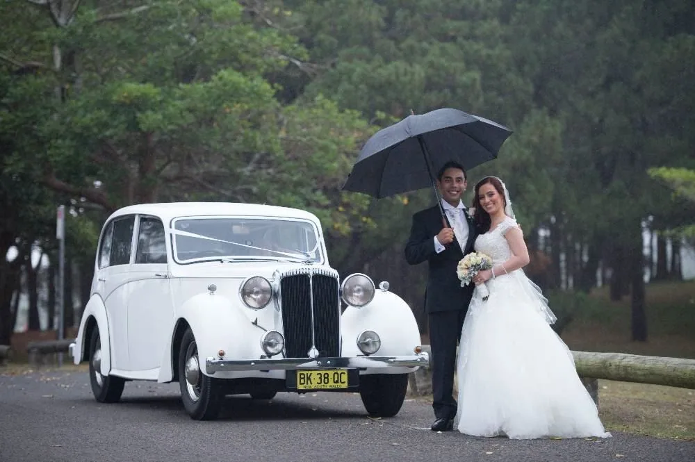 White Chrysler wedding car with wedding umbrella